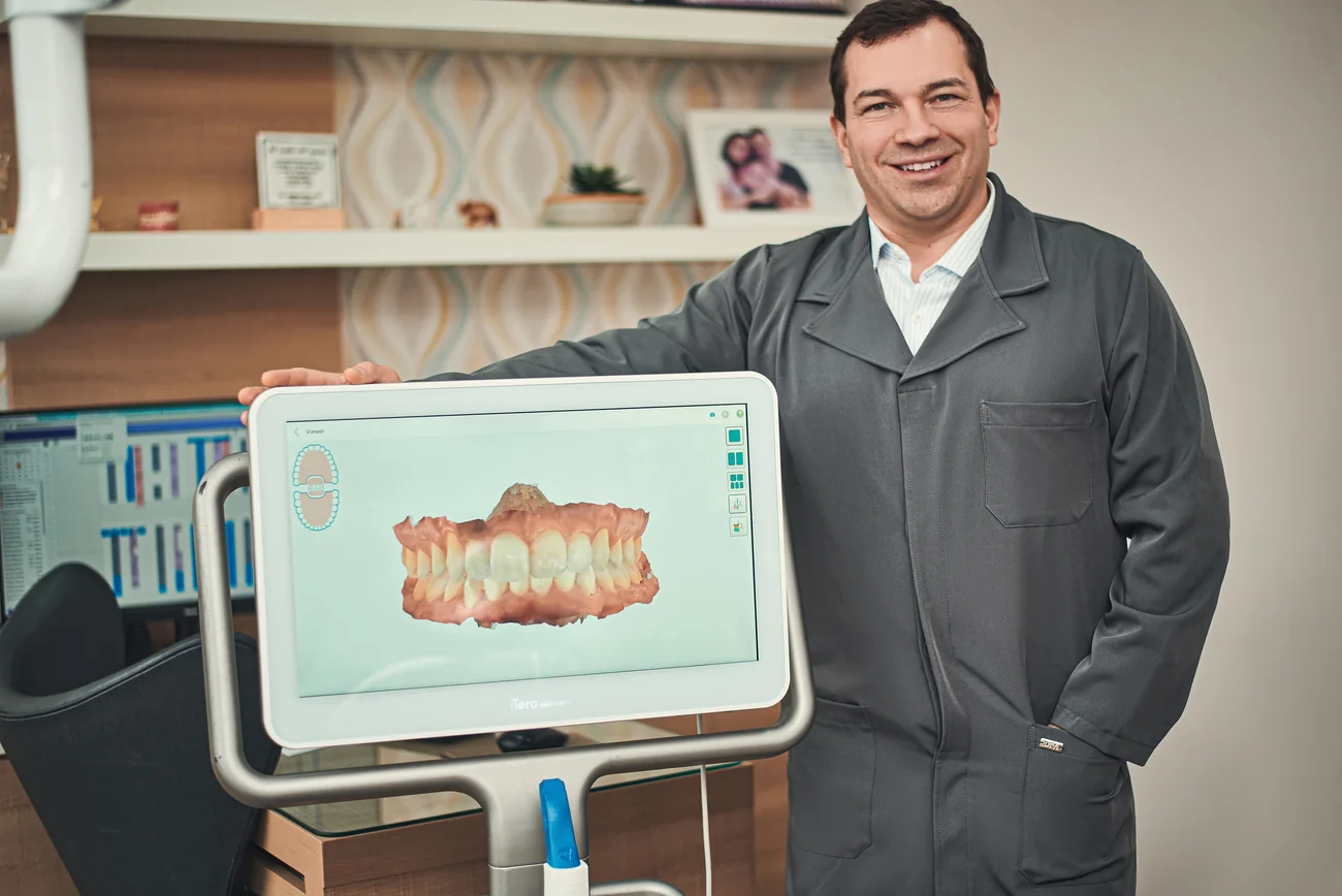 Charles Cavalheiro ao lado do scanner intraoral e de um modelo digital de arcadas
